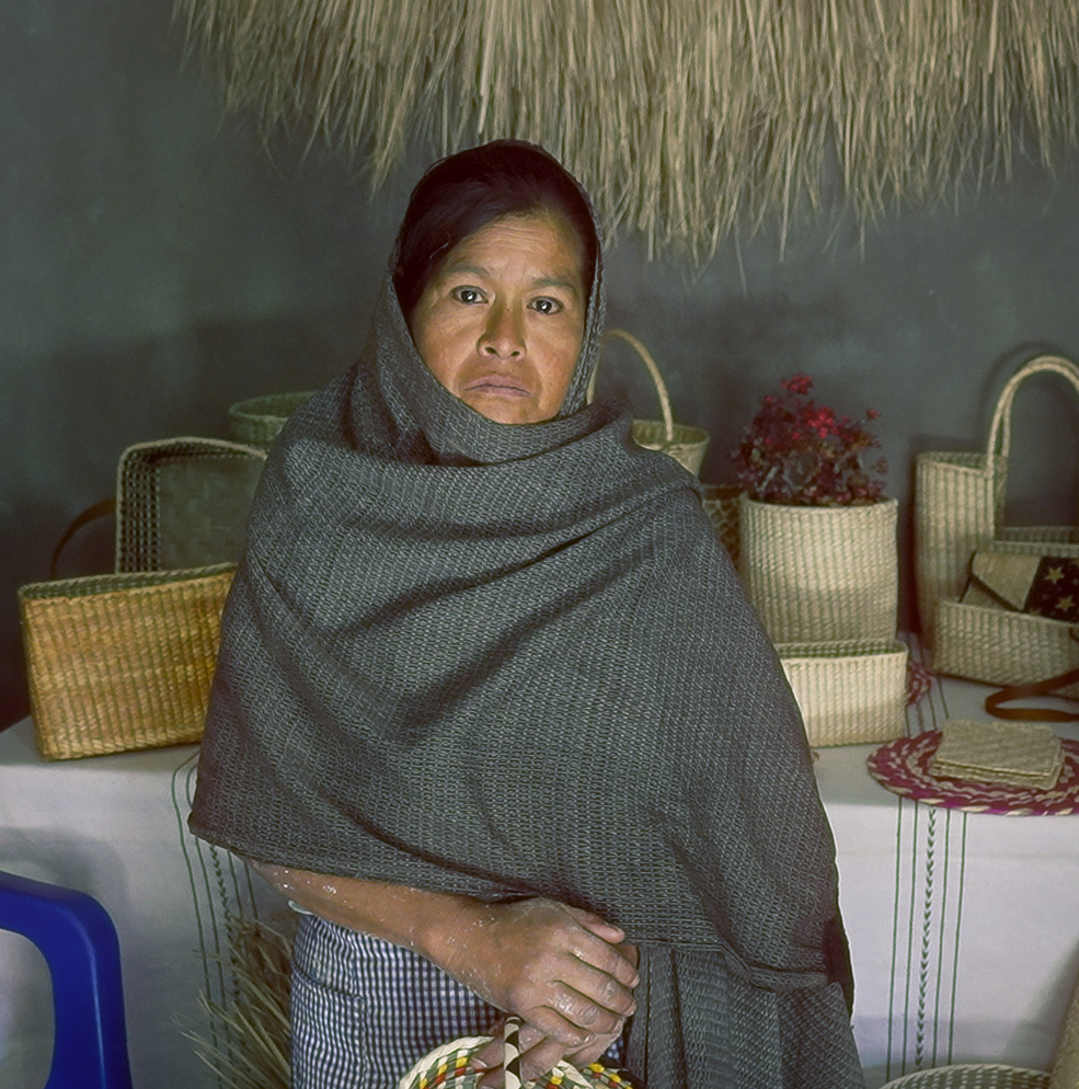 Artesana mexicana posando con sus obras de artesanía al fondo